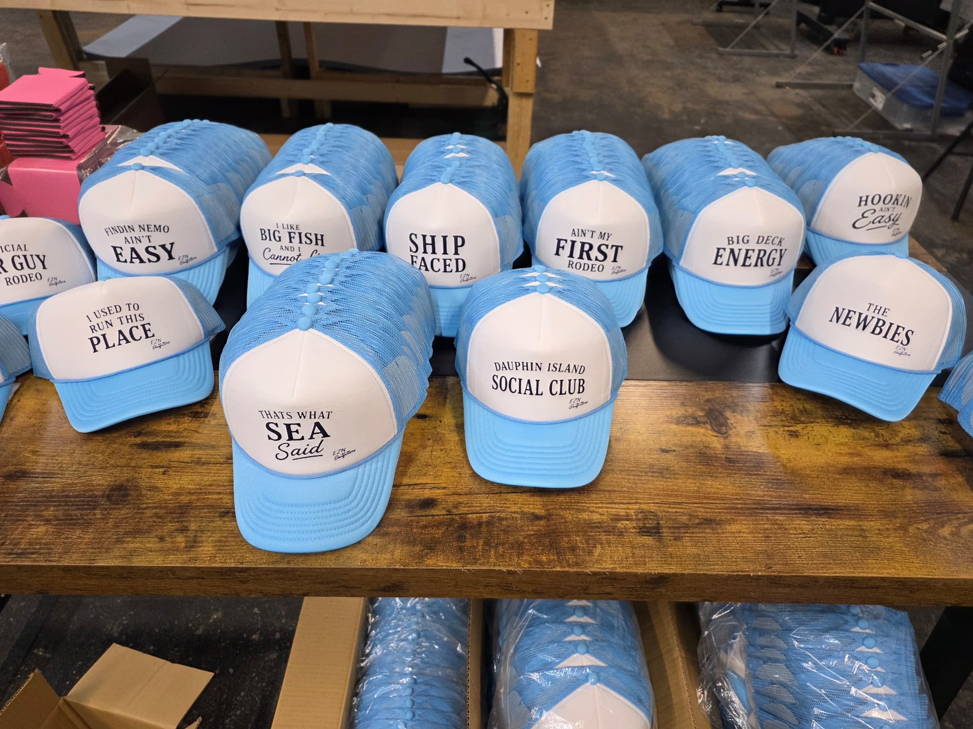 Close view of light blue foam trucker hats printed with Dauphin Island Social Club and other designs