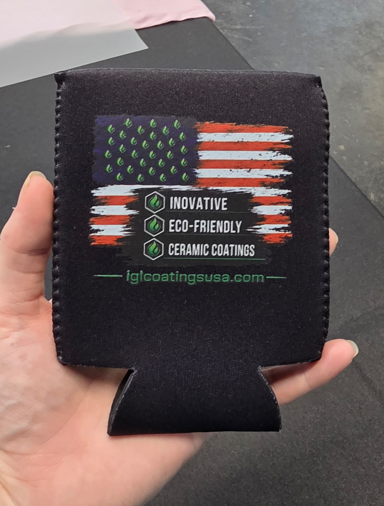 Black neoprene can koozie printed with an IGL Coatings USA flag design