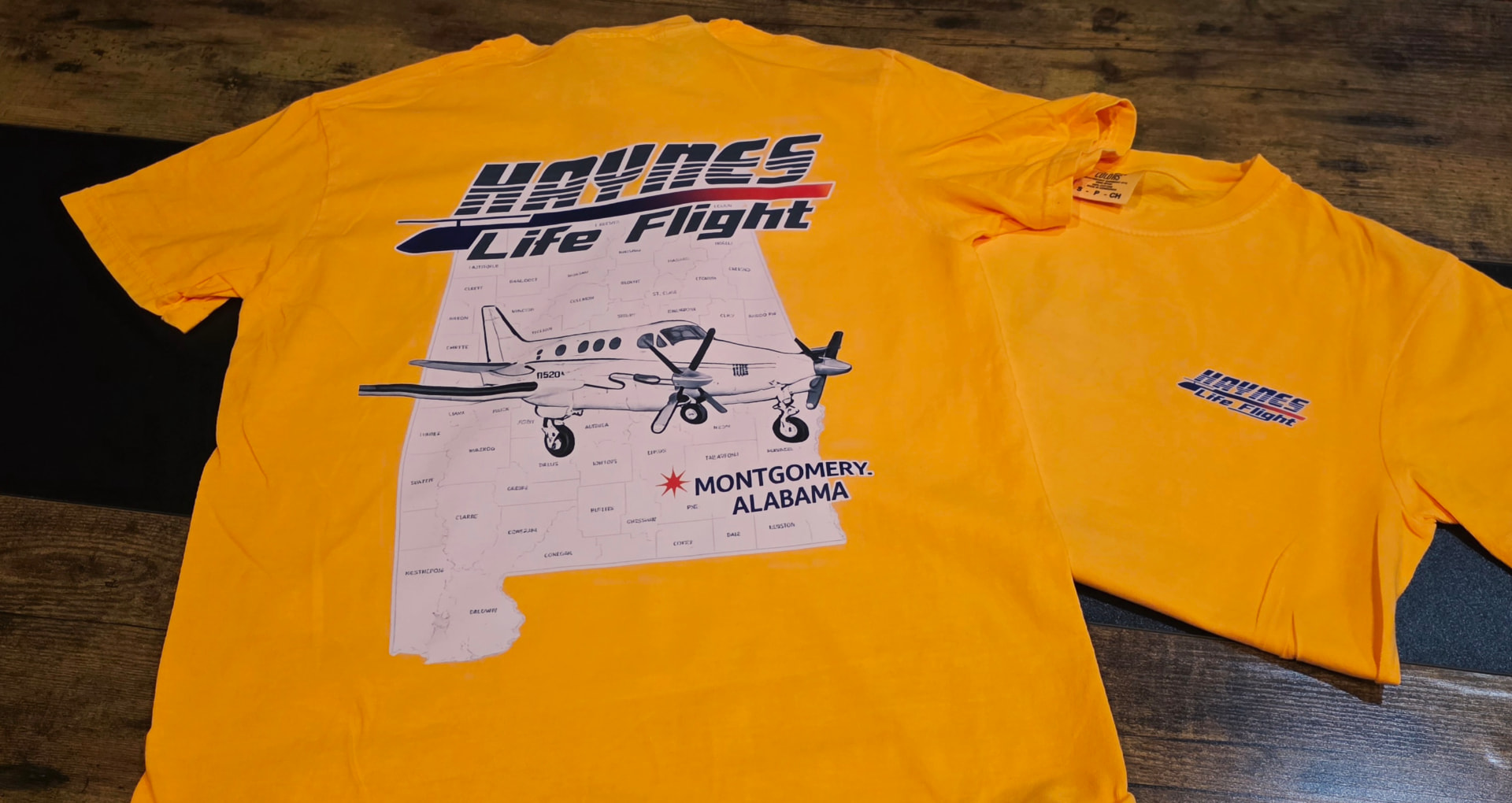 Gold t shirt printed with a Haynes Life Flight aircraft and Alabama map design
